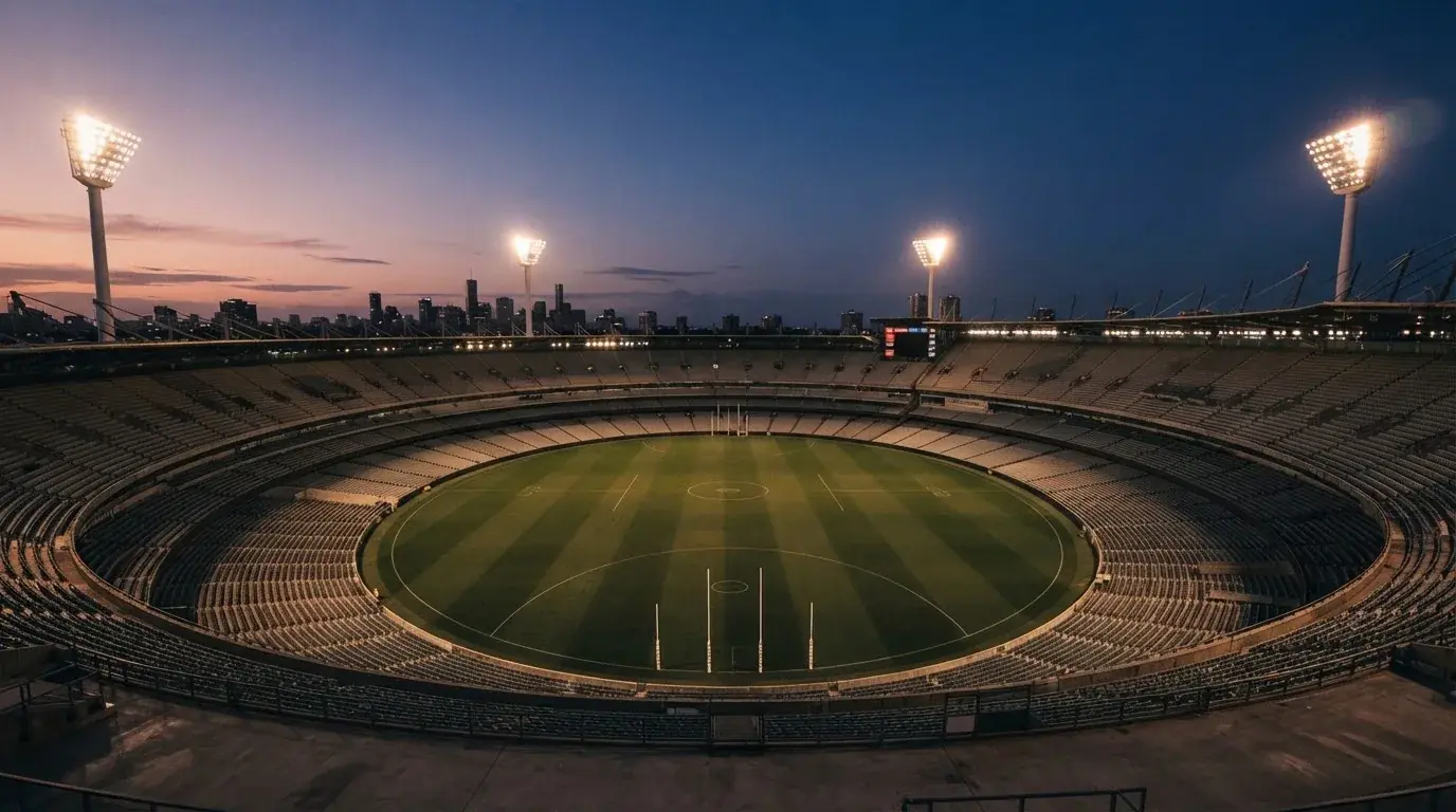 An empty football stadium with floodlight masts at dusk