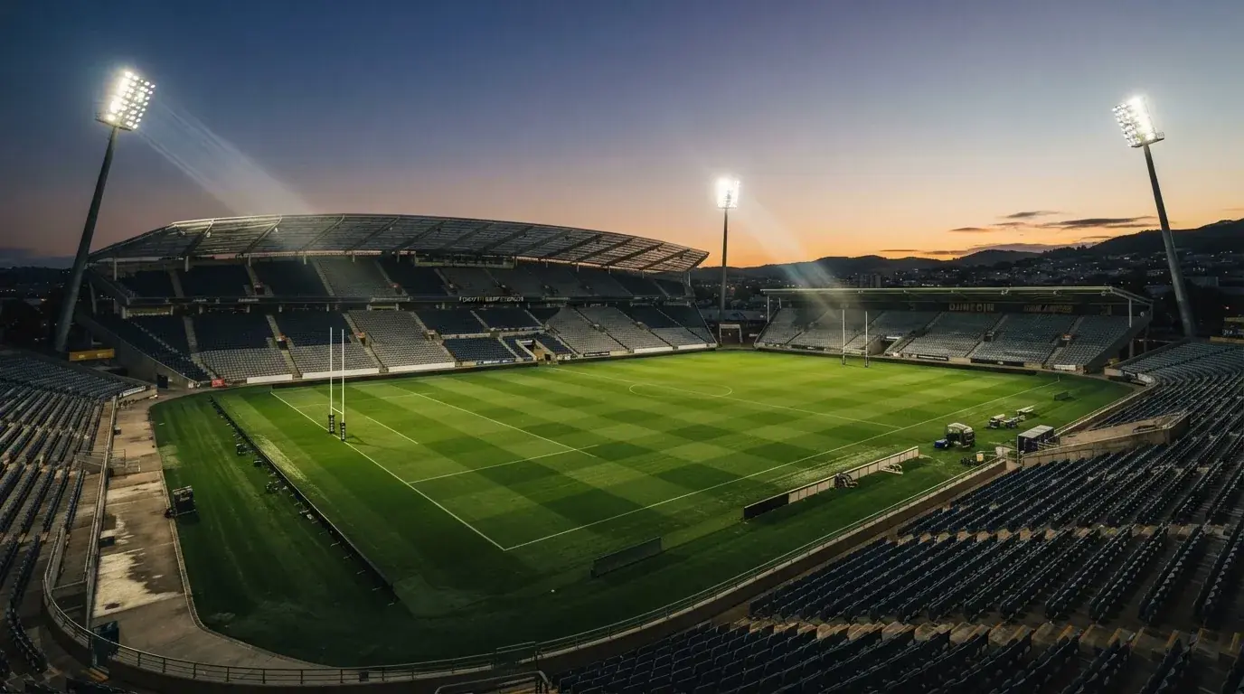 An empty football stadium with floodlight masts at dusk