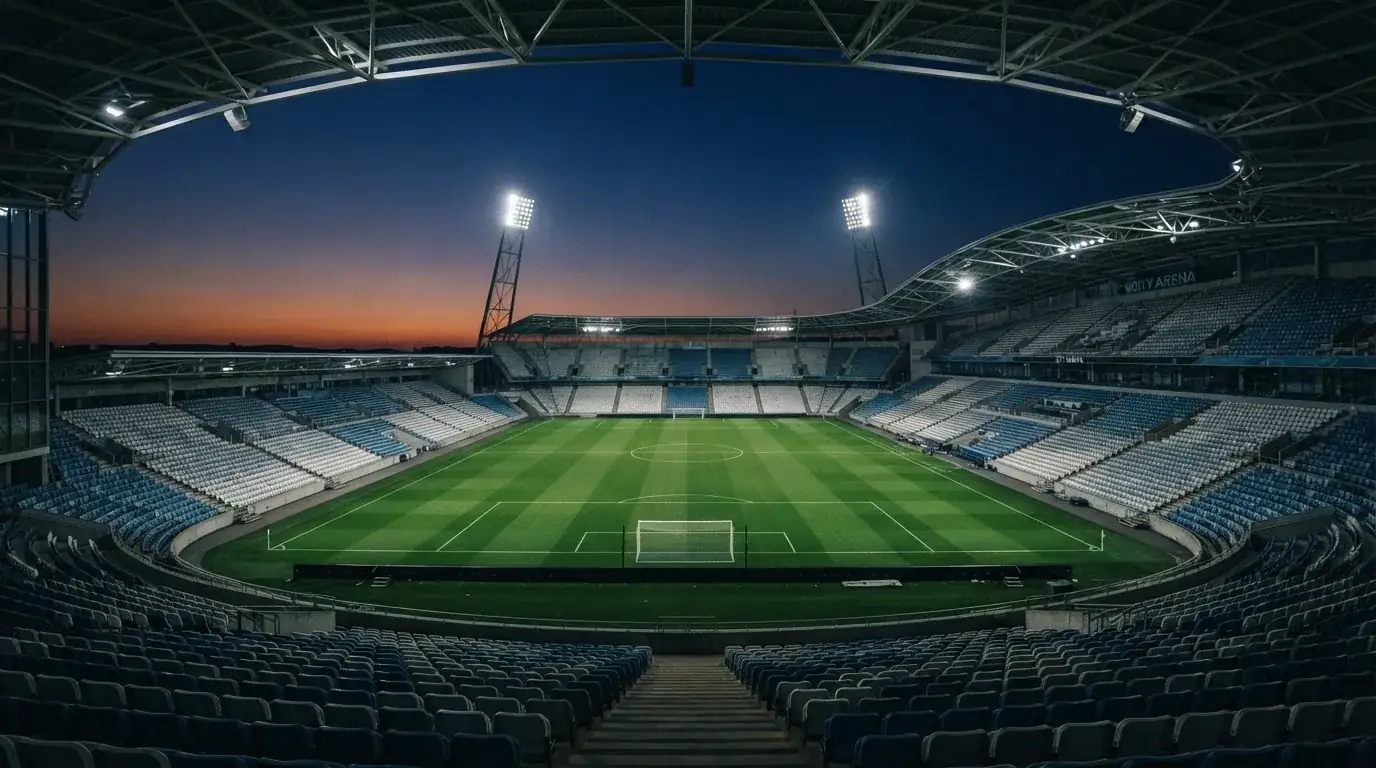 An empty football stadium with floodlight masts at dusk