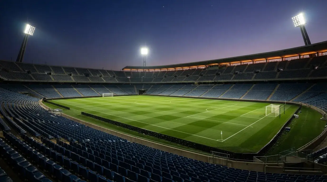 An empty football stadium with floodlight masts at dusk