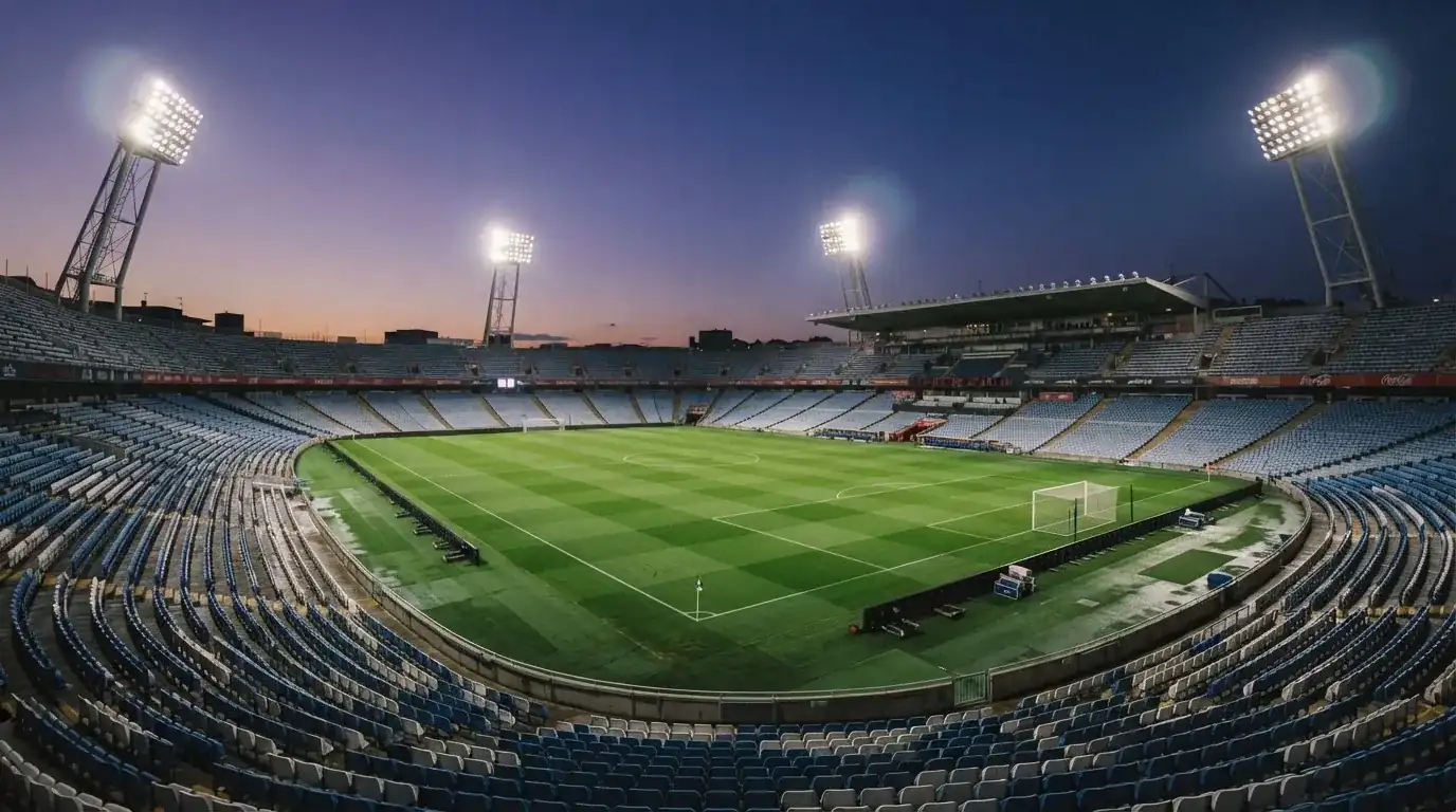 An empty football stadium with floodlight masts at dusk
