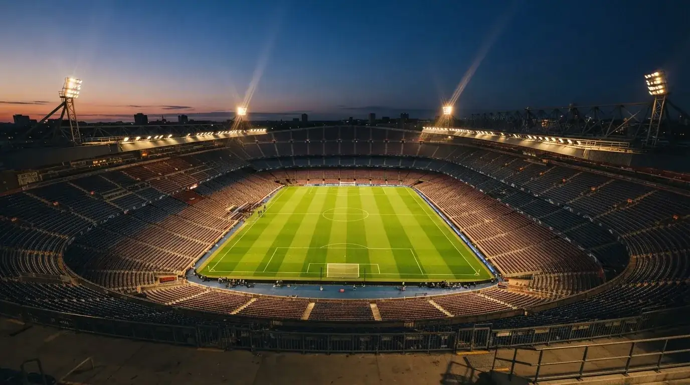 An empty football stadium with floodlight masts at dusk