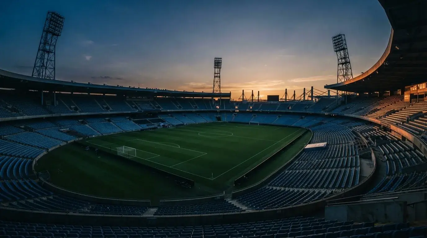 An empty football stadium with floodlight masts at dusk