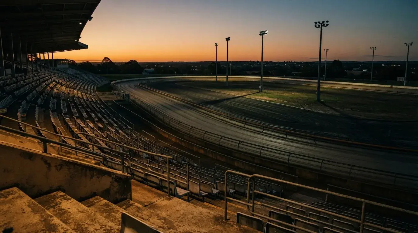 An empty football stadium with floodlight masts at dusk