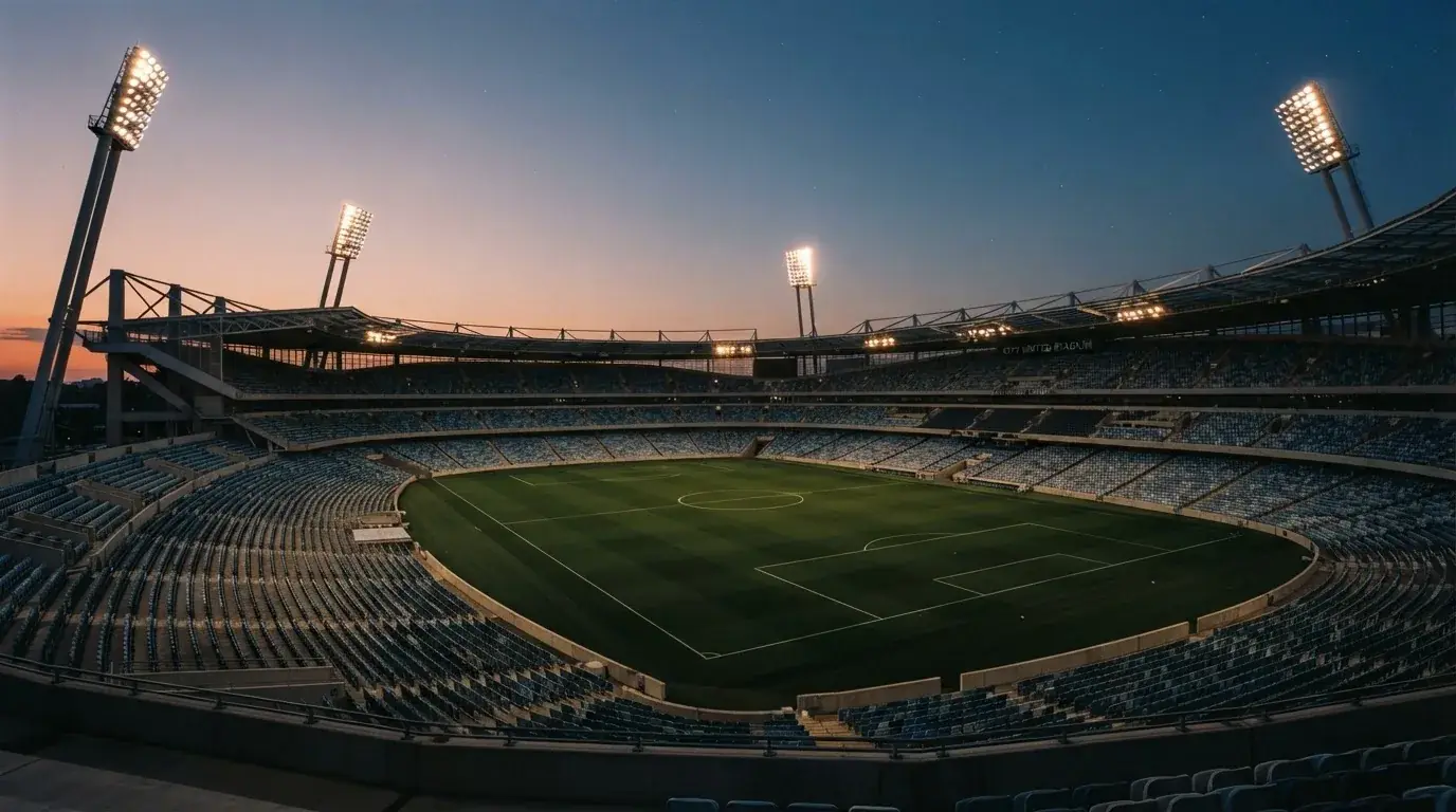 An empty football stadium with floodlight masts at dusk