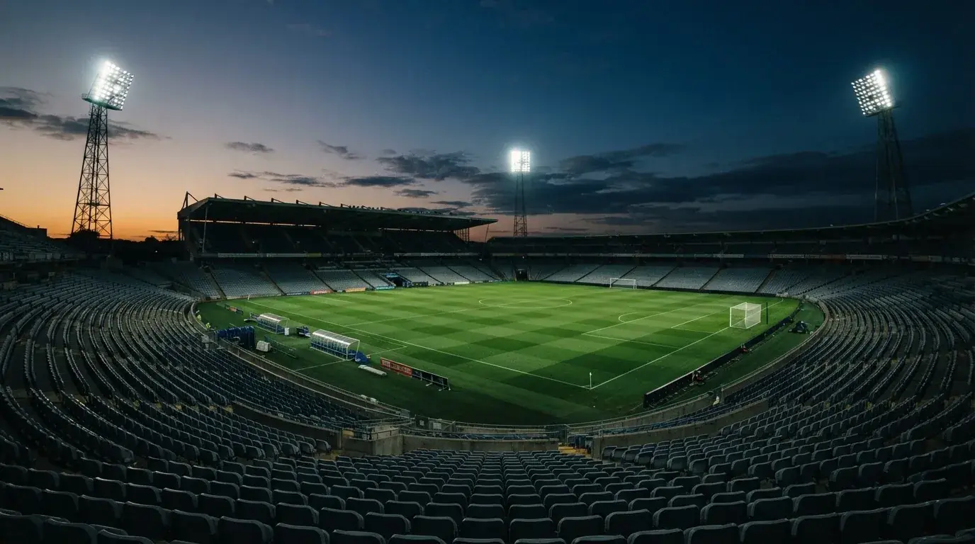 An empty football stadium with floodlight masts at dusk