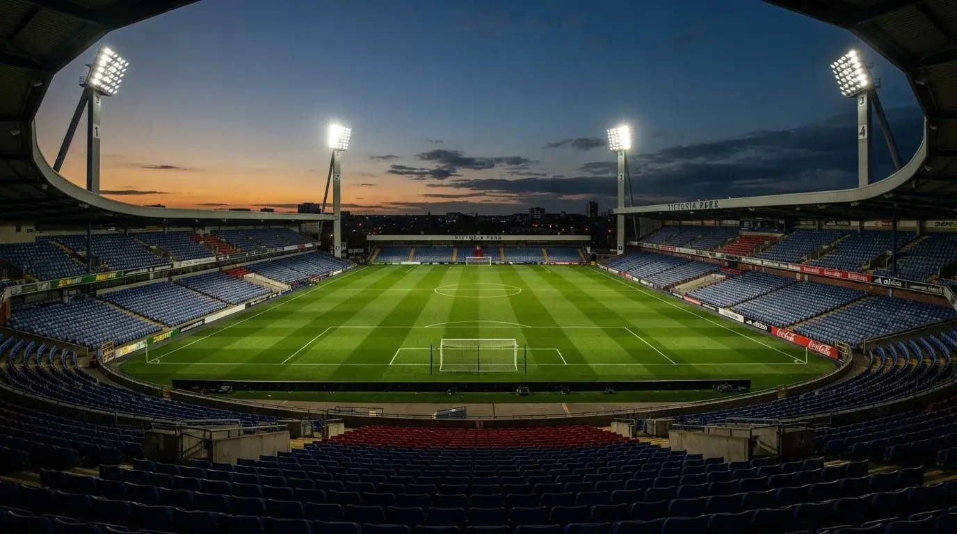 An empty football stadium with floodlight masts at dusk