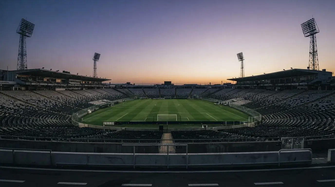 An empty football stadium with floodlight masts at dusk