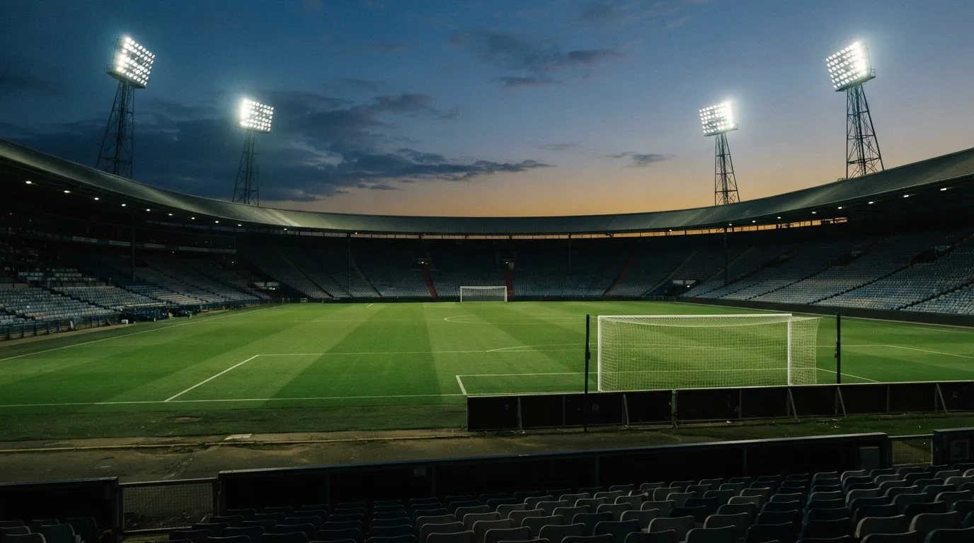 An empty football stadium with floodlight masts at dusk